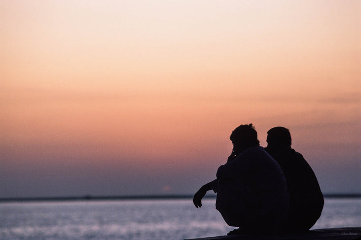 Two Men Squatting, Sea in Background, Abu Dhabi